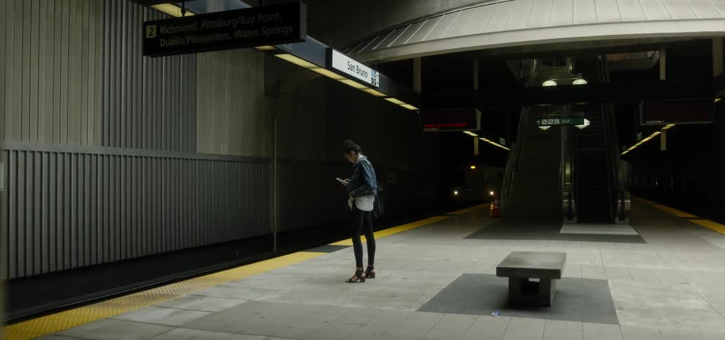 A woman standing on a subway platform using her phone
