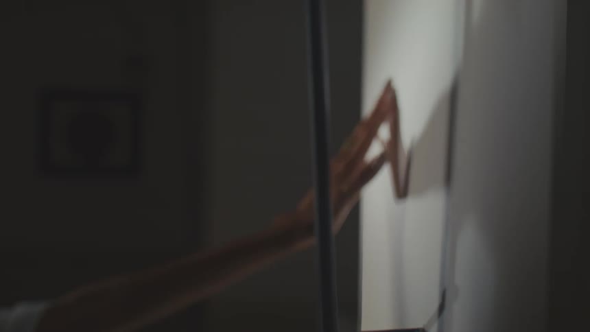 A womans hand pulls slowly away from a white wall