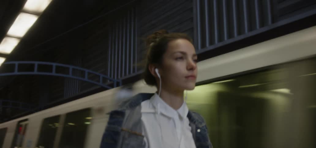 A woman is walking along a train platform