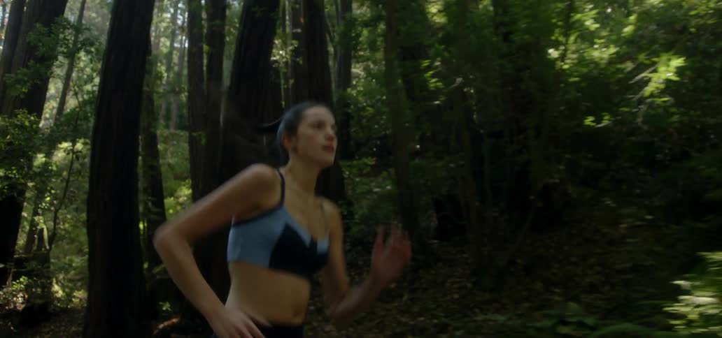 A woman runs through a forested area