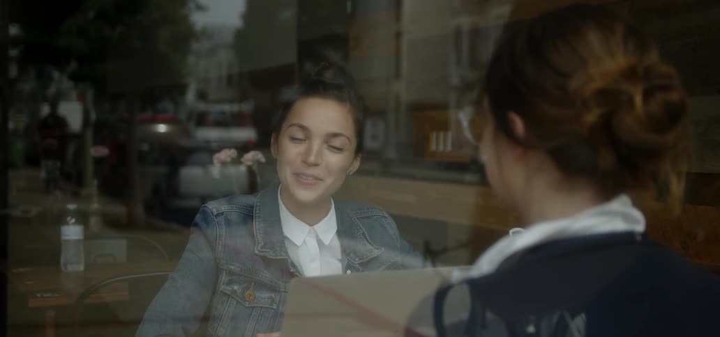 Two women talking while sitting at a table in a shop in the city