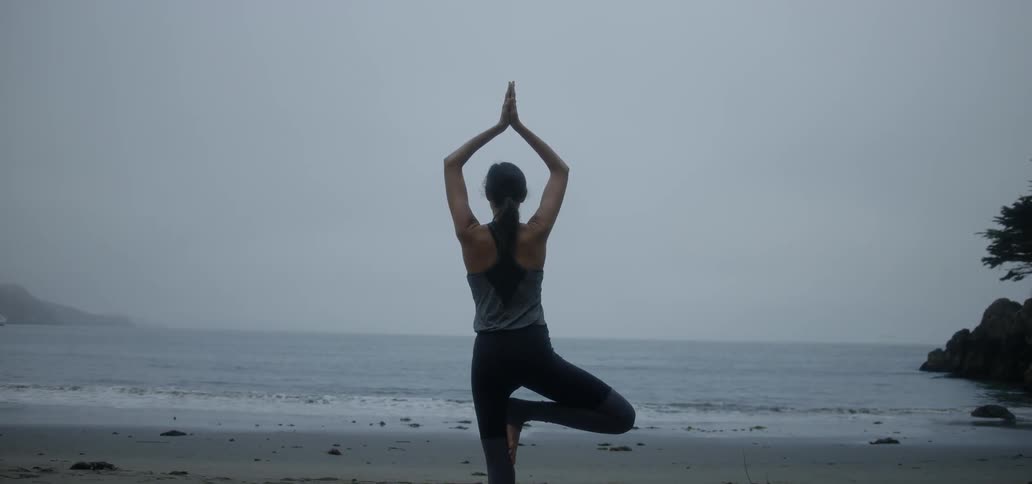 A woman does yoga on the beach