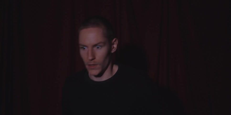 Man with hands on his head in a dark setting with low lighting