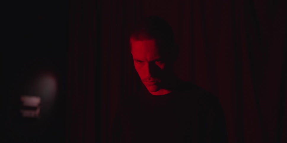 Man lit by red light against a dark background