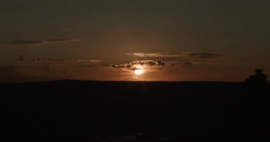 Low sun illuminating dense clouds above a dark horizon