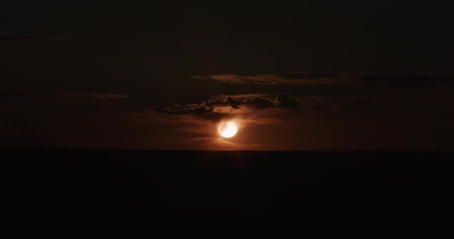 The sun shines through a dark cloudy sky