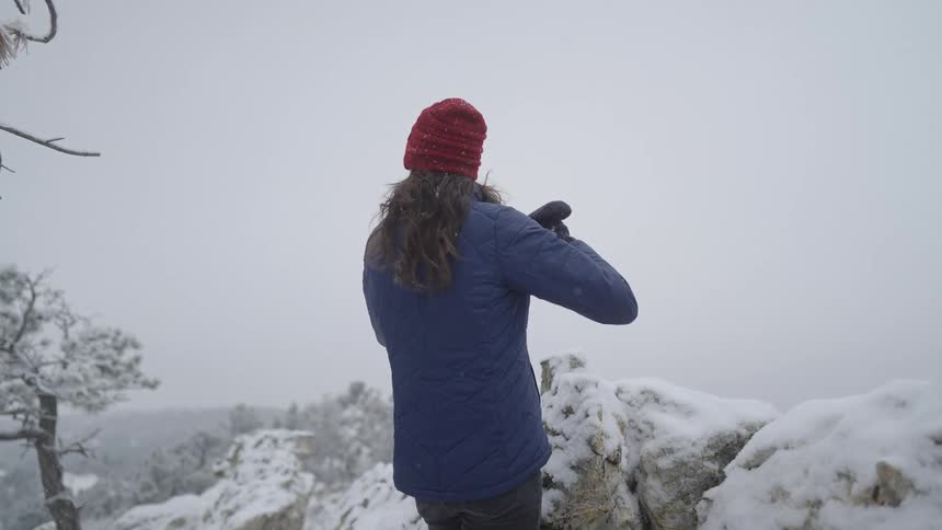 Person using binoculars on snowcovered rocks