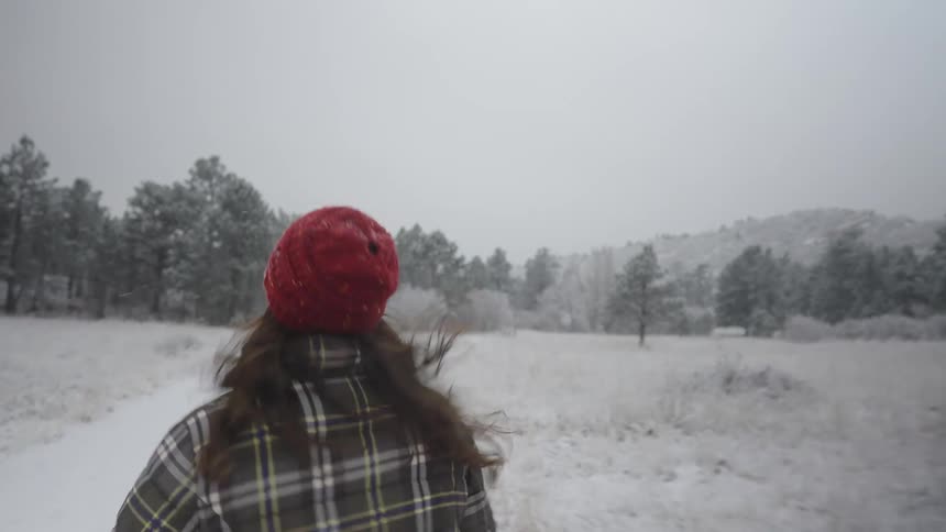 A woman running through a snow covered forest