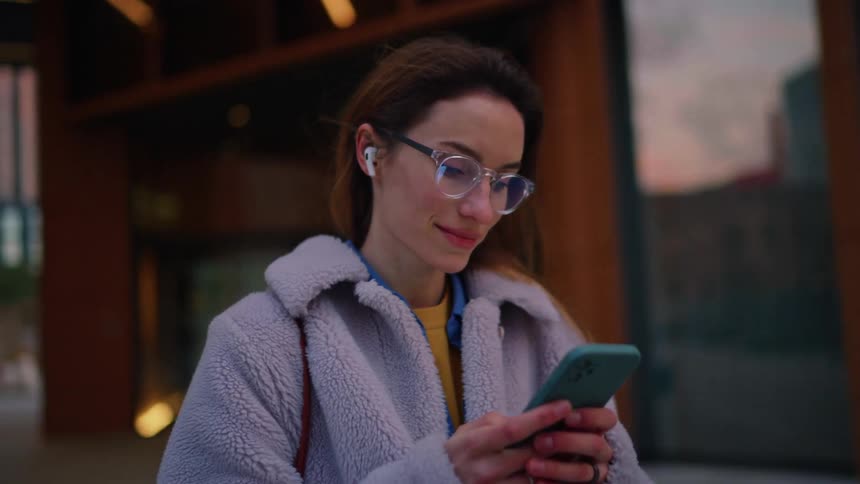Woman standing on a city street holding her phone and texting