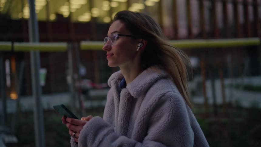 A woman walking in a city while using a phone
