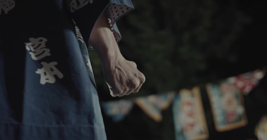 Person wearing traditional attire makes a clenched fist and opens their hand