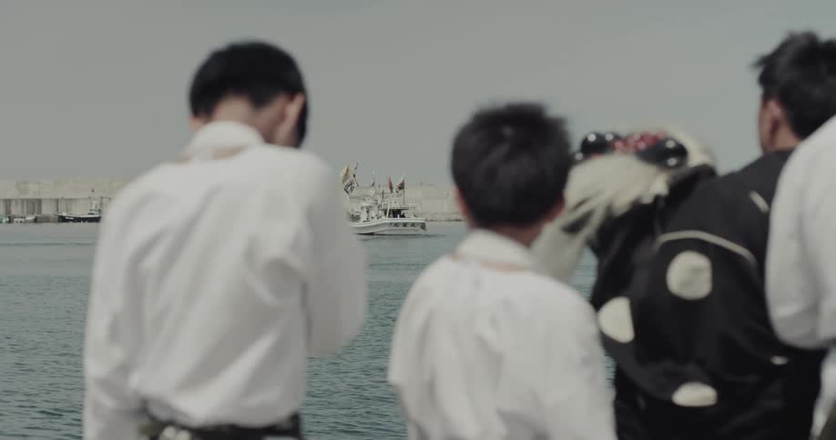 People watching a boat at sea from a coastal area