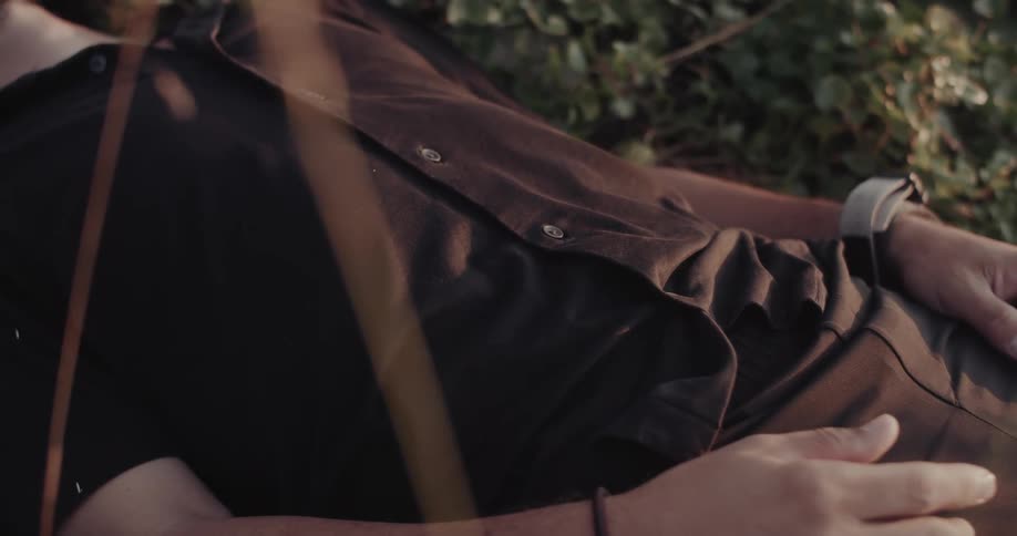 Person lying on grass with hand resting on the body in an outdoor setting