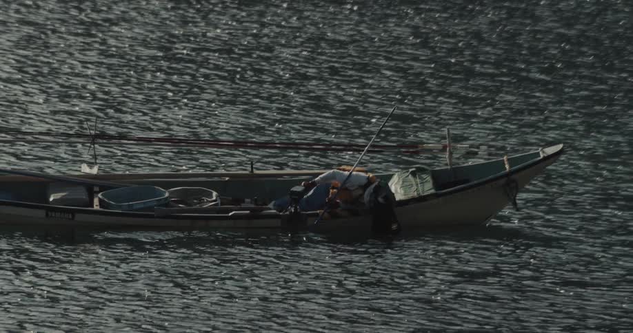 A fisherman fishing from a canoe at sea during daytime