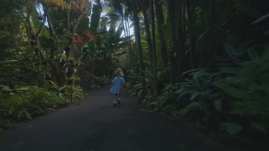 Child walks and sits on a wooden bench along a path in a tropical garden