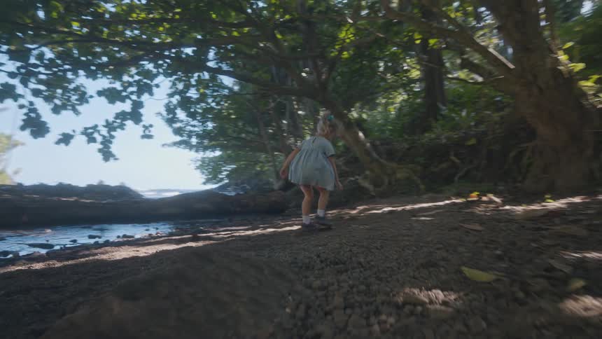 The girl runs and throws rocks in the small stream