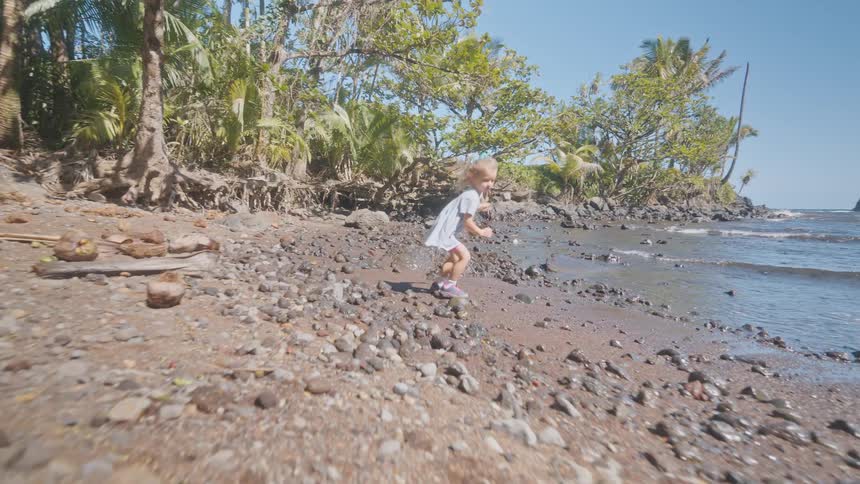 The young girl runs on the rocks of the beach