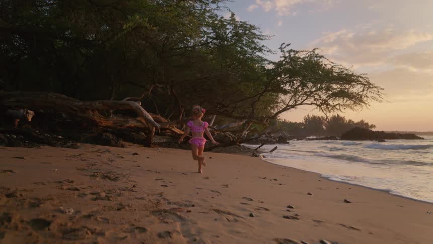 The girl runs towards driftwood on the beach