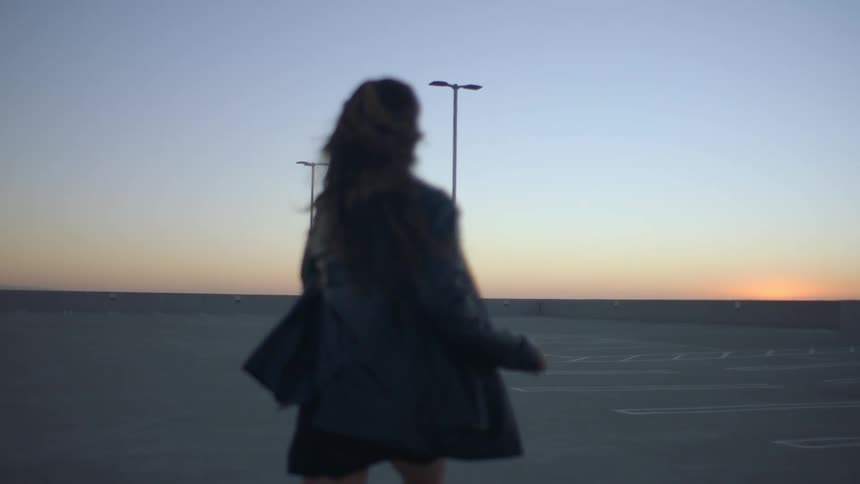 Woman runs in empty parking lot at sunset
