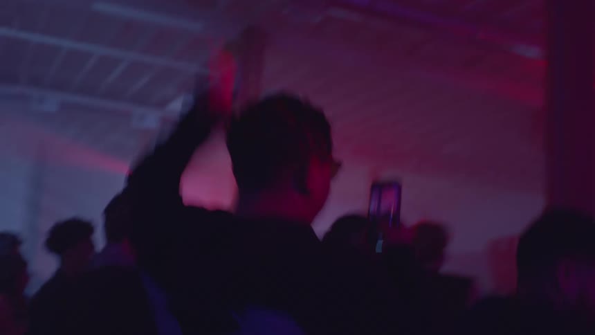 The man is dancing in the club while holding his cell phone