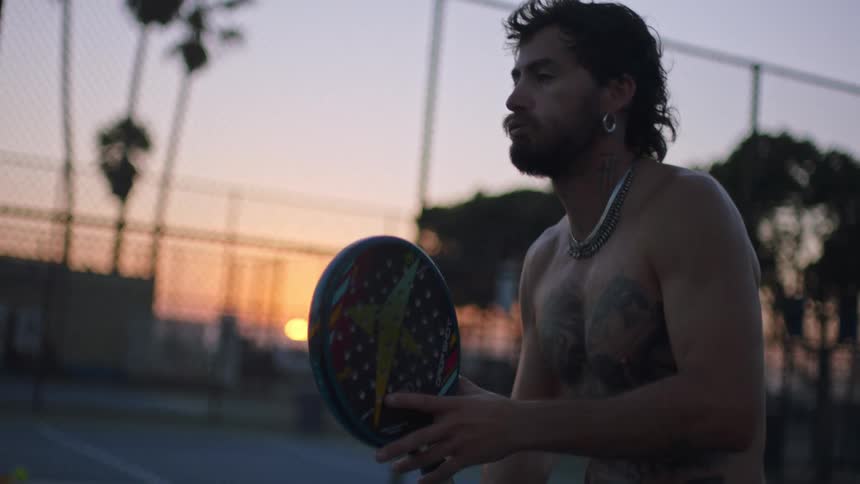 Shirtless man practicing sports while holding a racket
