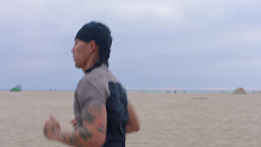 Small group of people jog on the beach past a food cart and pedestrians during the daytime