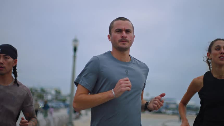 Three joggers run on the beach together