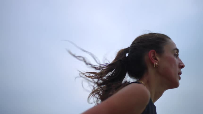 Close up portrait of a young woman with a ponytail jogging outdoors during daytime