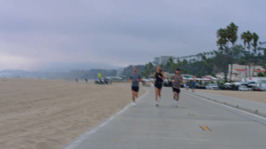 People jog on a road near the beach on a summer day