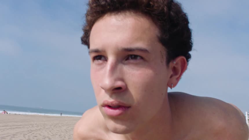 Close up portrait of a young male playing volleyball outdoors at the beach during daytime