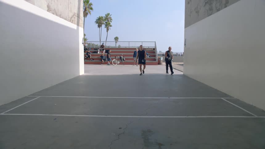 Two men playing american handball in an outdoor court during daytime