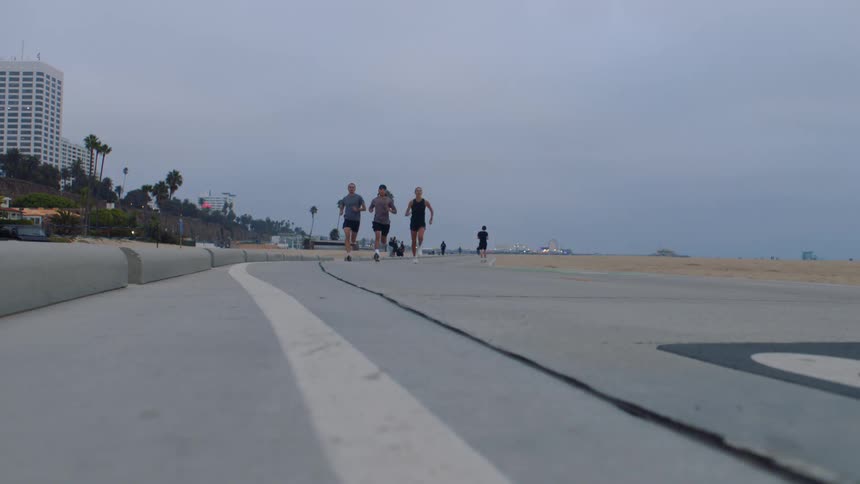 Three people running side by side at midday two young men and one young woman
