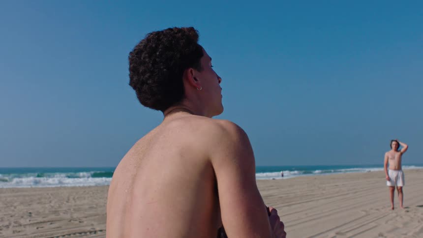 Man catching an american football while on the beach sand