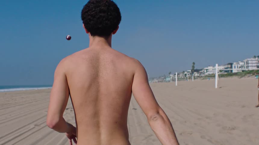 Man throwing an american football to a colleague while on the beach