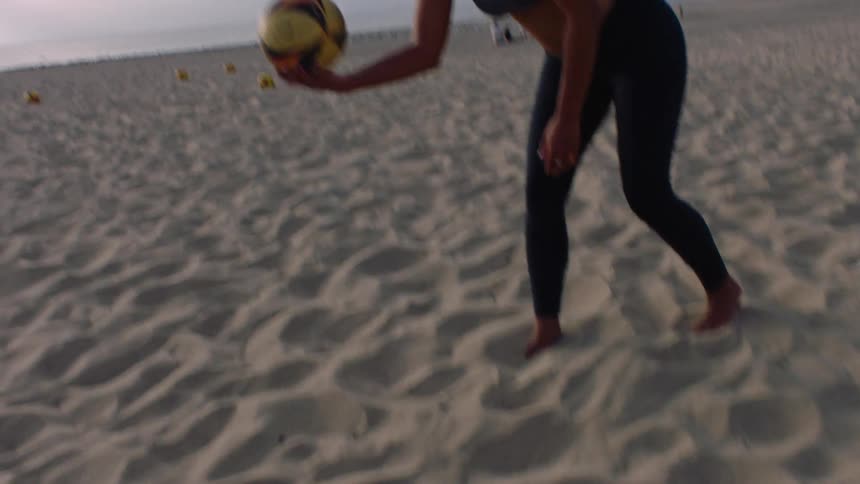 A group of friends playing beach volleyball on the sandy court under a clear sky