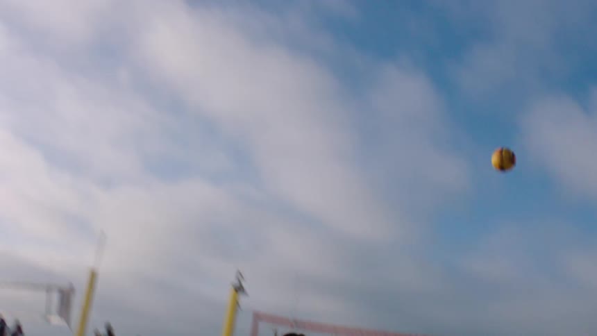 Four women playing beach volleyball on a sandy court under a cloudy sky