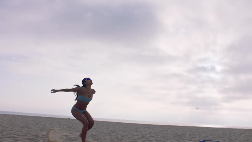 A young asian woman playing volleyball outdoors at the beach during daytime