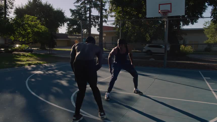 Man playing basketball with a partner and missing the basket on an outdoor court