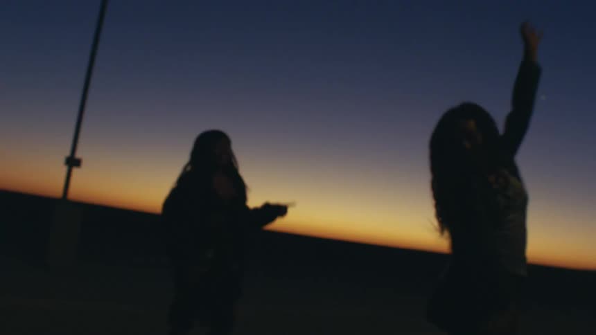 Women dance outdoors on the beach at night