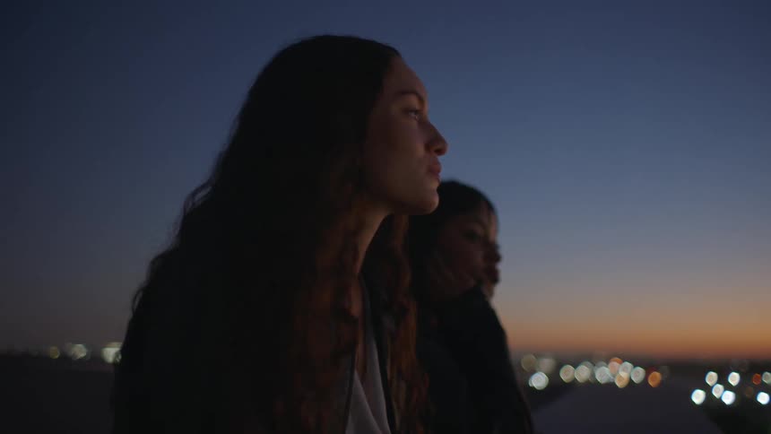 Two women sitting outdoors at dusk