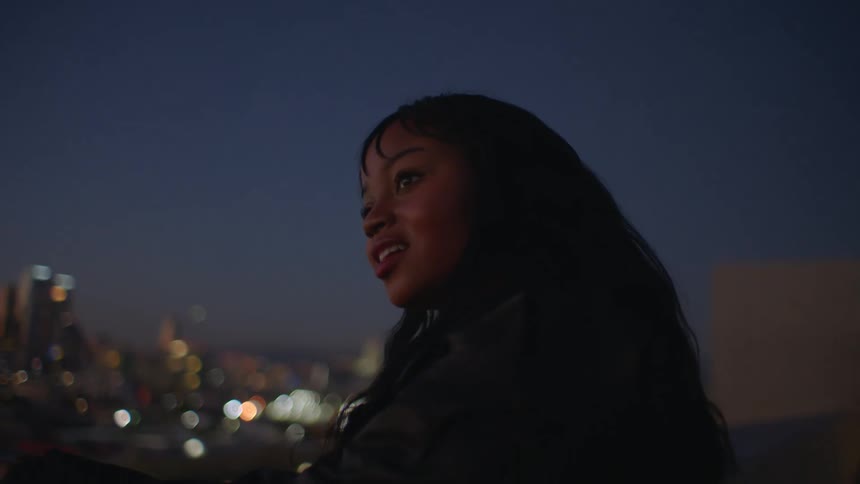 Woman in a building observing the skyline of a metropolis at night