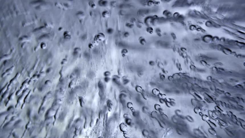 Translucent ice with scattered bubbles and wavy patterns seen in closeup