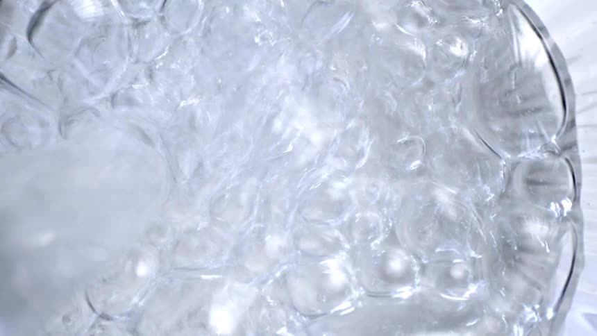 Top view of clear liquid in motion inside a container with textured walls