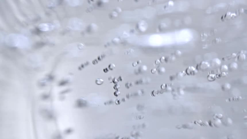 Air bubbles arranged in lines inside clear liquid seen in closeup