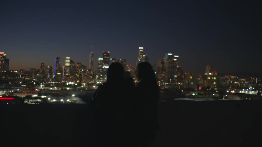 A silhouette of two people in front of a city