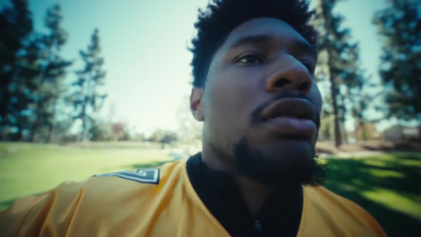 Man in profile outdoors in a park with trees in the background during daytime