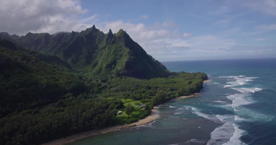 A lush mountainous coastline contains several beach houses