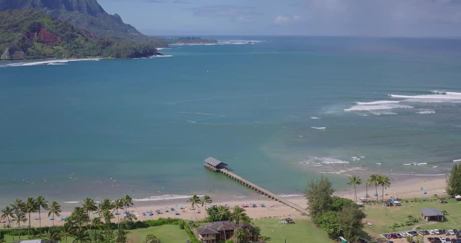 Aerial view of a tropical coastline with turquoise waters and palm lined homes below coastal mountains