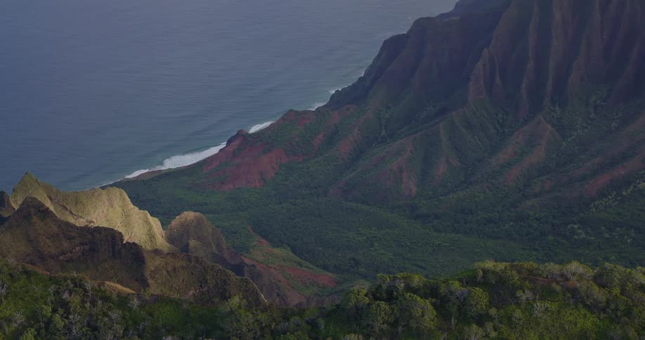 Aerial view of a tropical coastal cliff descending into the ocean under soft daylight