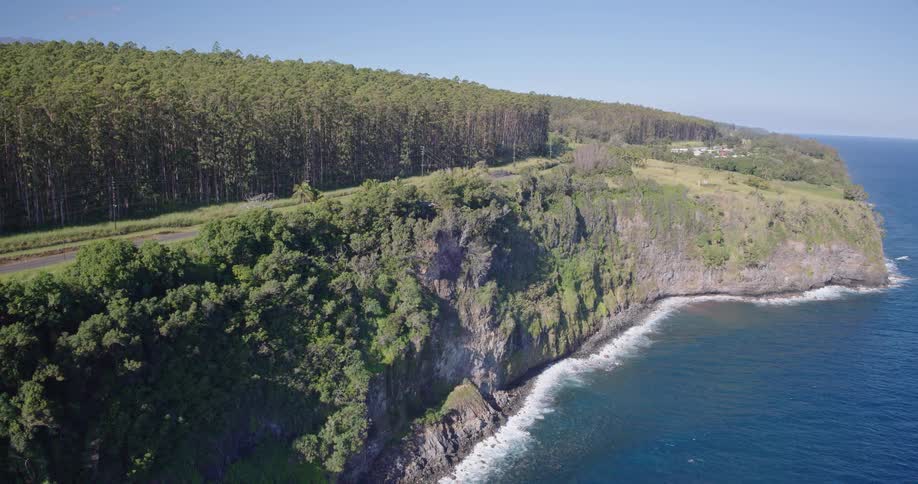 The first line is the rugged edge of the cliff which creates a dramatic boundary between the lush green landscape and the deep blue ocean water belowthe second line is the paved road that stretches horizontally across the top of the cliff separating